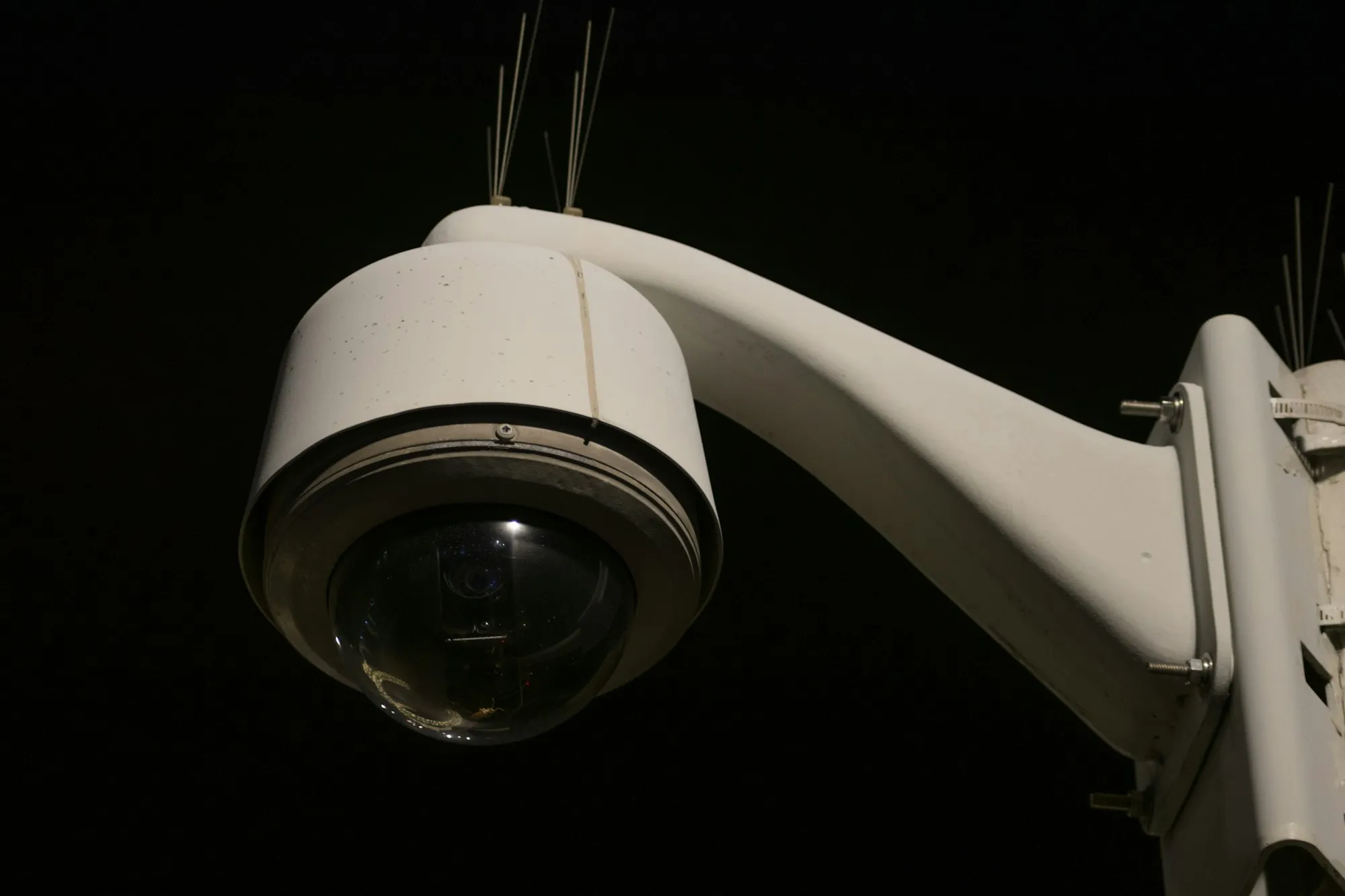 PTZ dome surveillance camera on a wall bracket at night