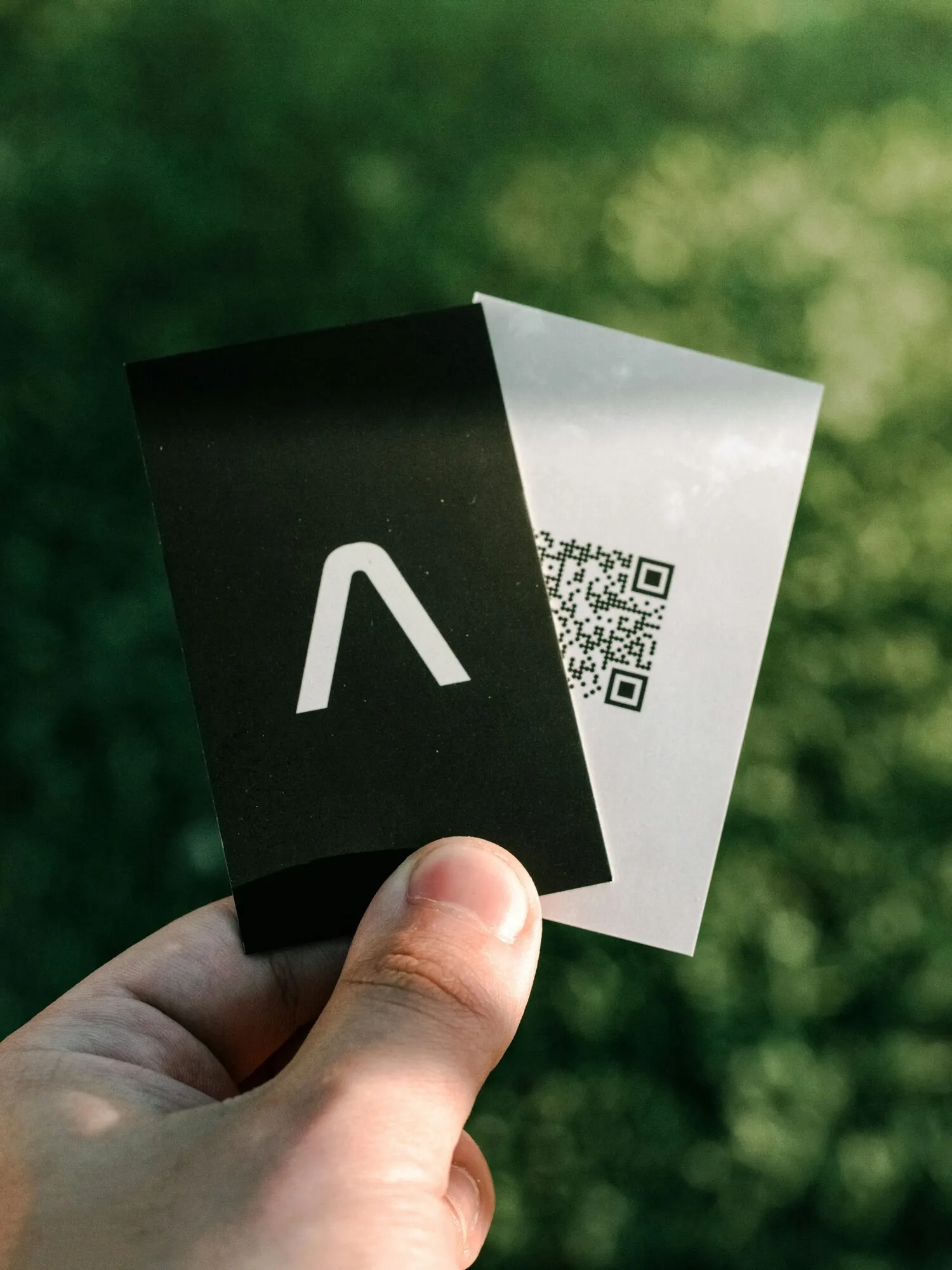 Hand holding a black business card and a card with a QR code